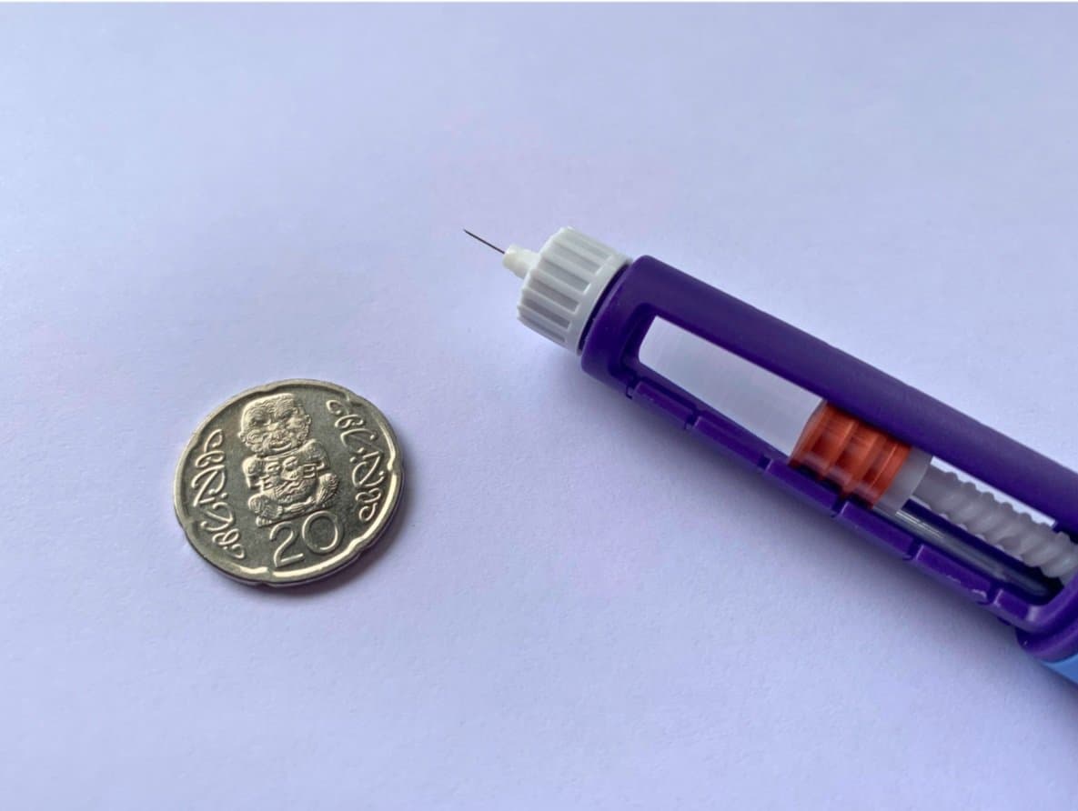 A Saxenda pen showing it's tiny needle with a coin for scale