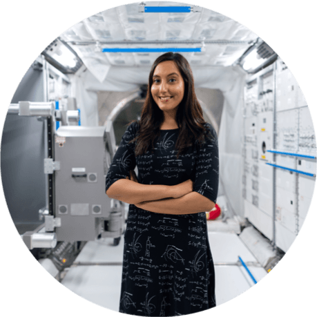 A smiling woman in a lab with her arms crossed.