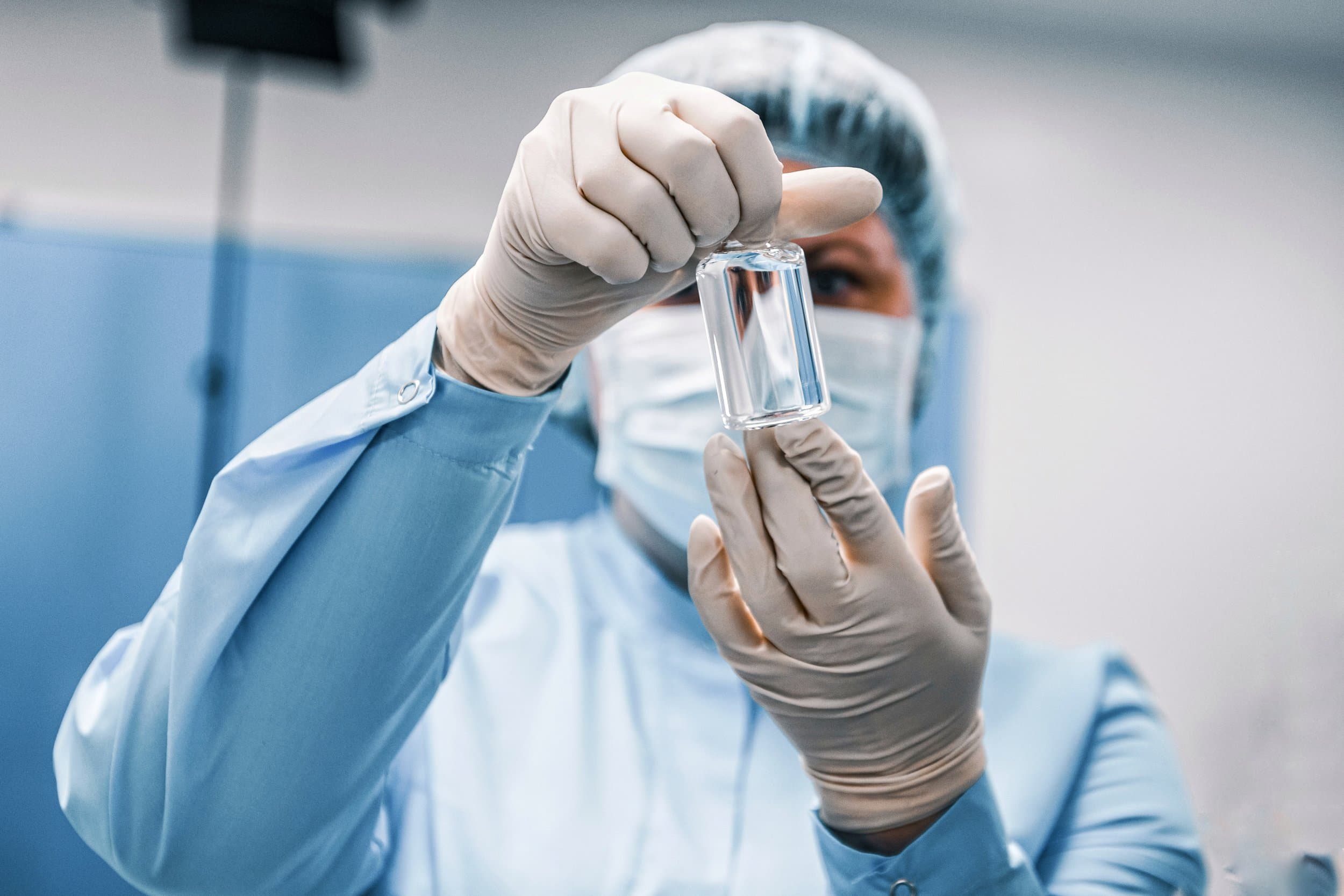 Close-up of a vial being held by a lab technician in the background.